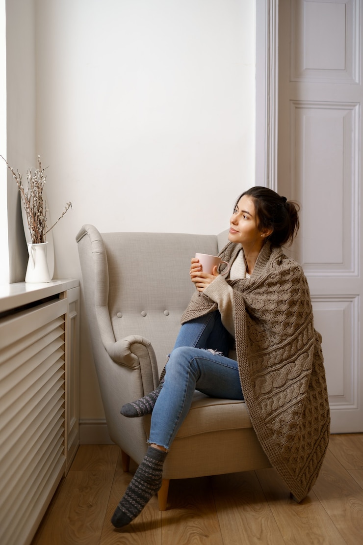 Free Photo smiling lady in smart trendy wear is sitting on armchair with a cup of tea.