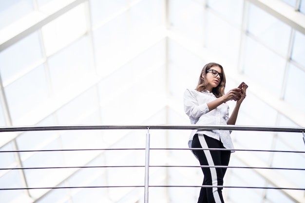 Smiling lady successful business women standing resting and looking through on balcony in modern office centre dressed up in white t-shirt