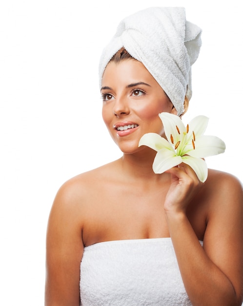 Smiling lady wrapped in towel holding lily