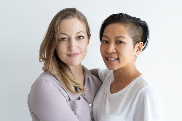 Smiling lesbian couple embracing and looking at camera