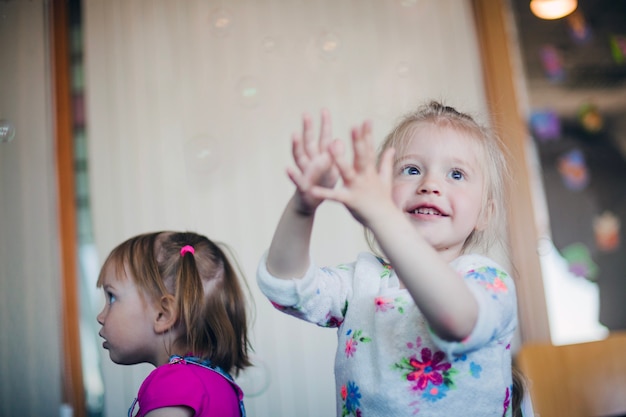 Free photo smiling little girl catching soap bubbles