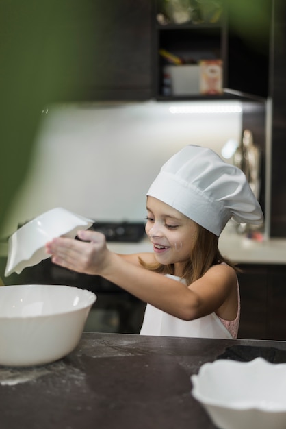 Smiling little girl mixing ingredients in bowl on kitchen worktop