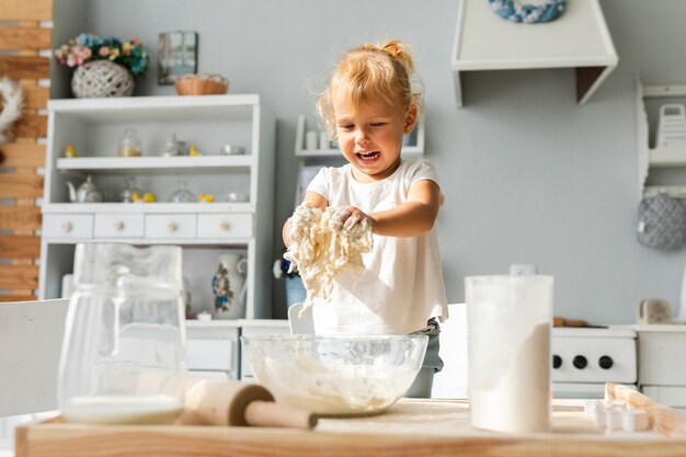 Улыбающаяся маленькая девочка готовит тесто