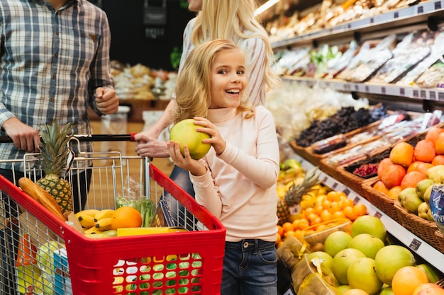 Улыбается маленькая девочка, ходить по магазинам для продуктов