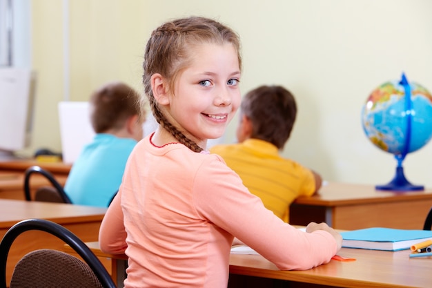 Free photo smiling little girl with classmates blurred background