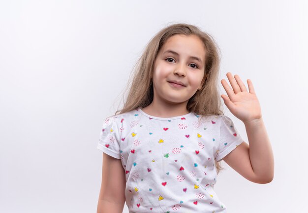 Smiling little school girl wearing white t-shirt showing hello gesture on isolated white background