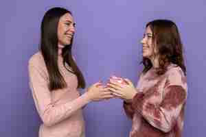 Free photo smiling looking at each other two girls holding presents