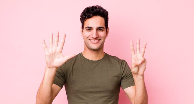 Smiling and looking friendly showing number eight or eighth with hand forward counting down