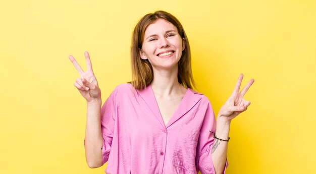 Smiling and looking happy friendly and satisfied gesturing victory or peace with both hands