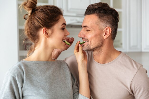 Smiling lovely couple cooks together on kitchen and feeding to each other