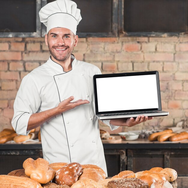 Smiling male baker standing in front of table with different type of breads