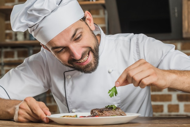 Smiling male chef decorating food plate