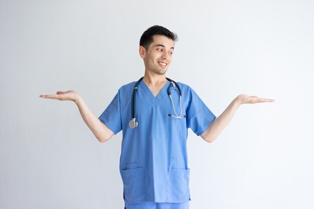 Улыбающийся мужчина-врач держит пустое пространство обеими руками