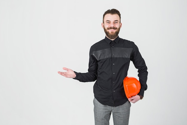 Free photo a smiling male engineer holding hardhat shrugging