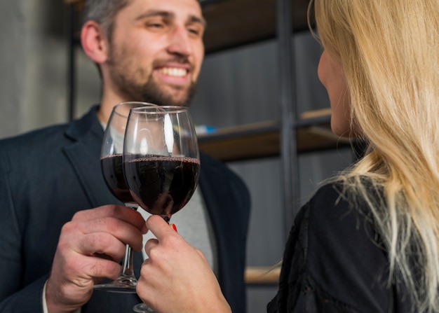 Free photo smiling male and female clanging glasses of drink in room