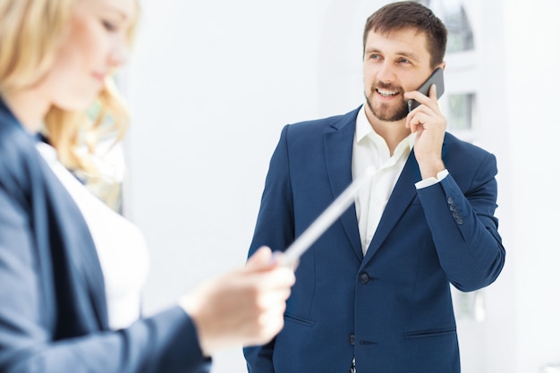 The smiling male and female office workers with laptop and phone