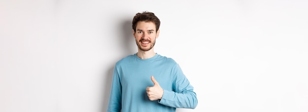 Free photo smiling male model in casual shirt showing thumb up approve and recommend product praise excellent c