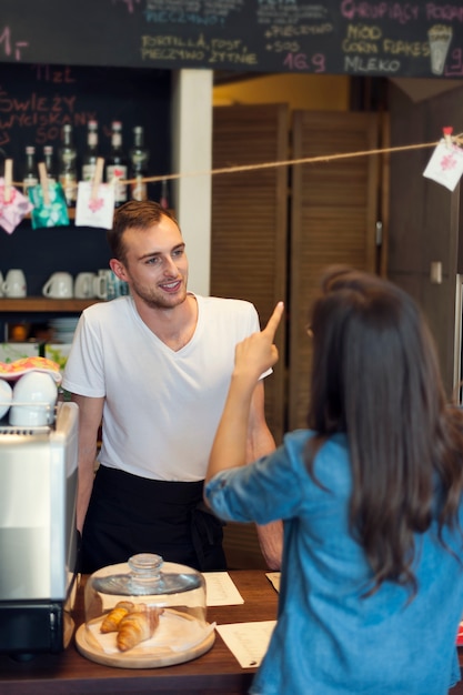 Smiling male waiter receives order from young woman 

