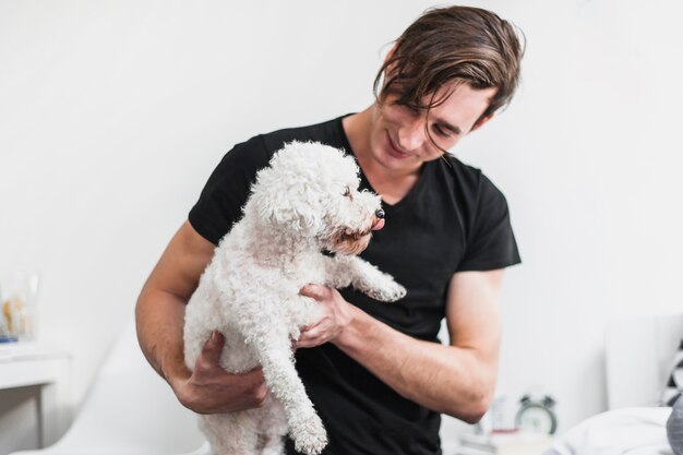 Smiling man carrying toy poodle in hands