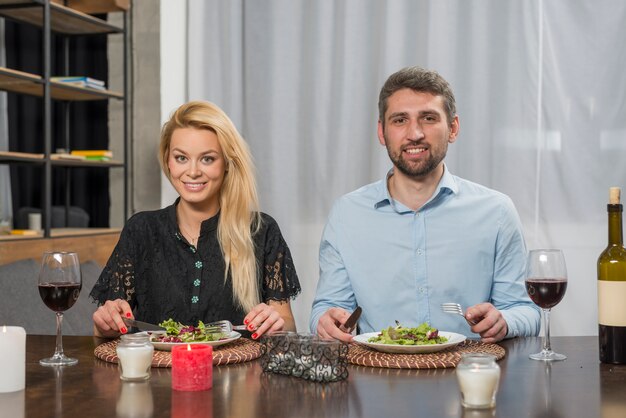 Smiling man and cheerful woman near plates at table