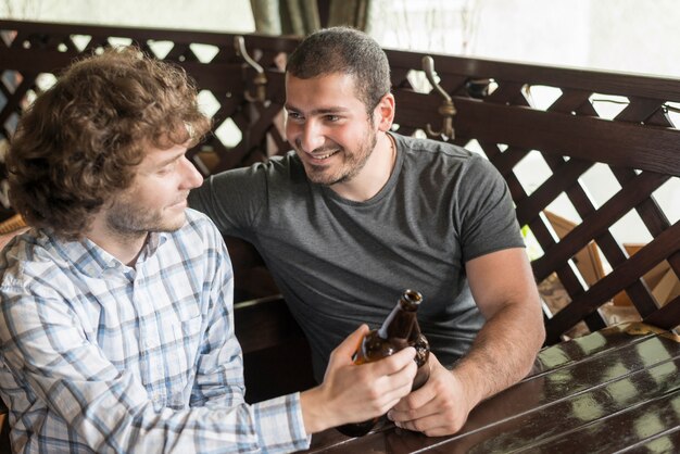 Улыбающийся человек звон бутылки с другом в баре