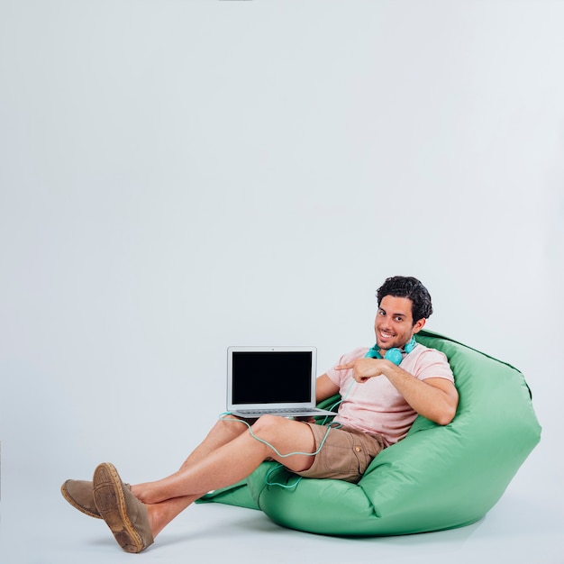 Улыбающийся человек на диване, представляя ноутбук