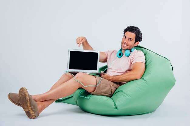 Smiling man on couch showing laptop