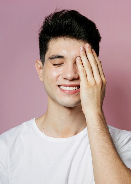 Smiling man covering half face with hand