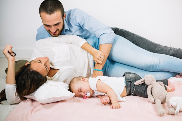 Smiling man embracing sleeping wife and baby