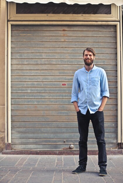 smiling man in front of a shop shutter