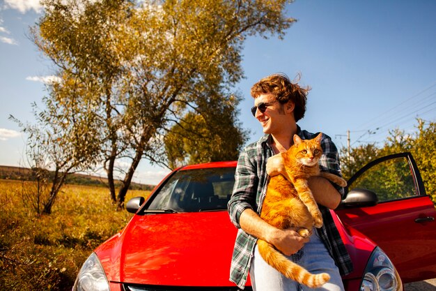 車の前に猫を持って笑みを浮かべて男