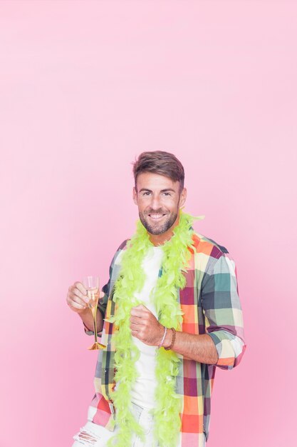 Smiling man holding champagne flute posing against pink background