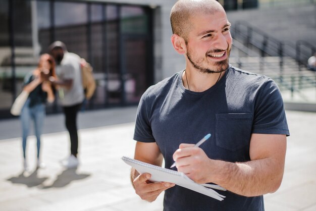 Smiling man holding notebook writing