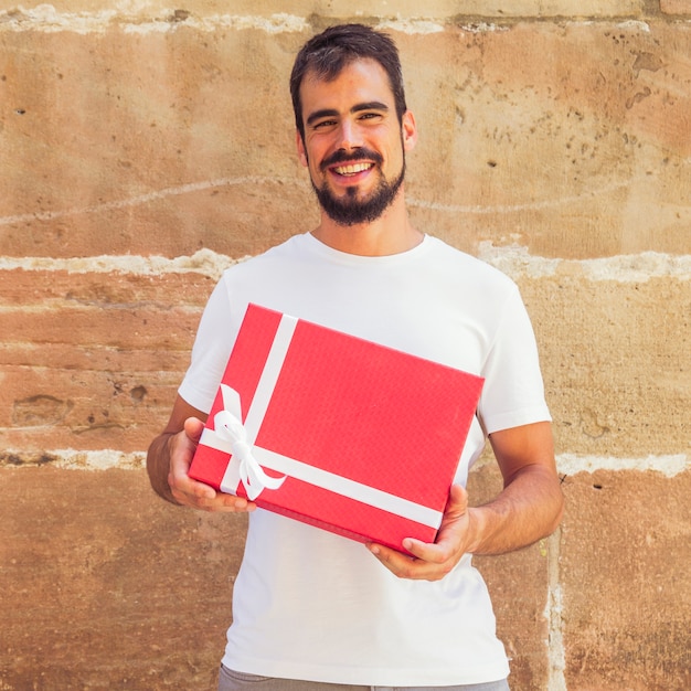 Smiling man holding red gift box