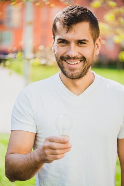 Smiling man holding transparent light bulb