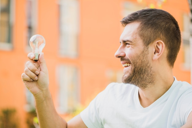 Smiling man holding transparent light bulb