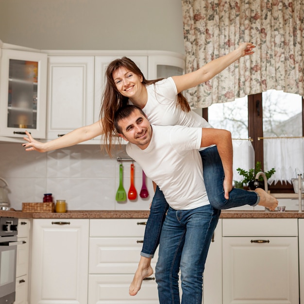 Free photo smiling man holding woman on his back