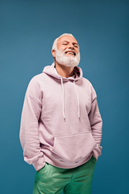 Smiling man in hoodie posing on isolated wall