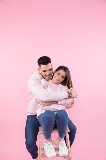 Smiling man hugging cheerful young woman on stool