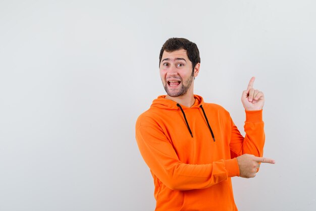 The smiling man is pointing sideways with forefingers on white background