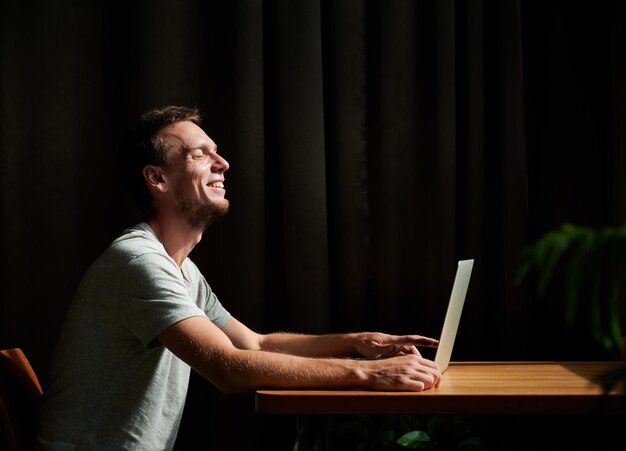 Smiling man is working on laptop at home