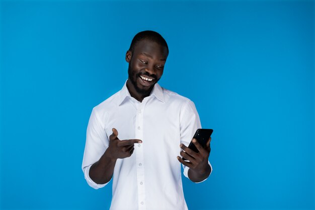 Smiling man keeps the phone and looks at it