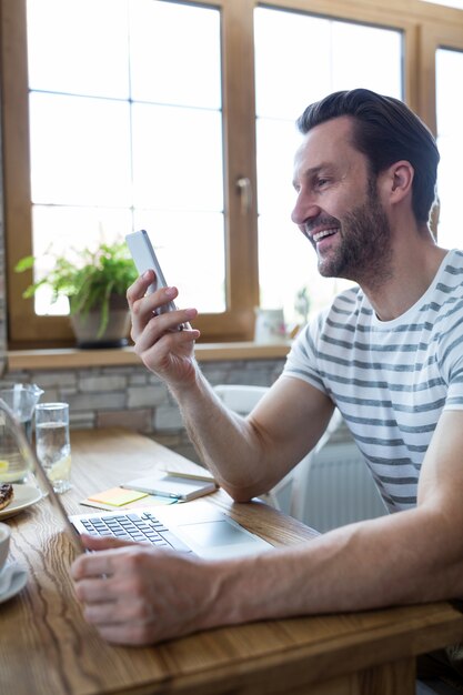 コーヒーショップで自分の携帯電話を見て笑顔の男