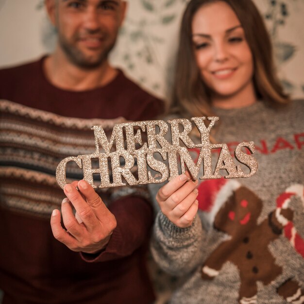 メリークリスマスのサインと陽気な女性の近くの笑顔の男