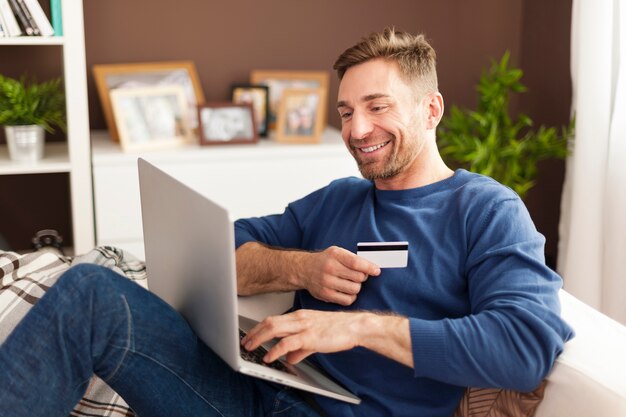Улыбающийся человек во время покупок в Интернете дома
