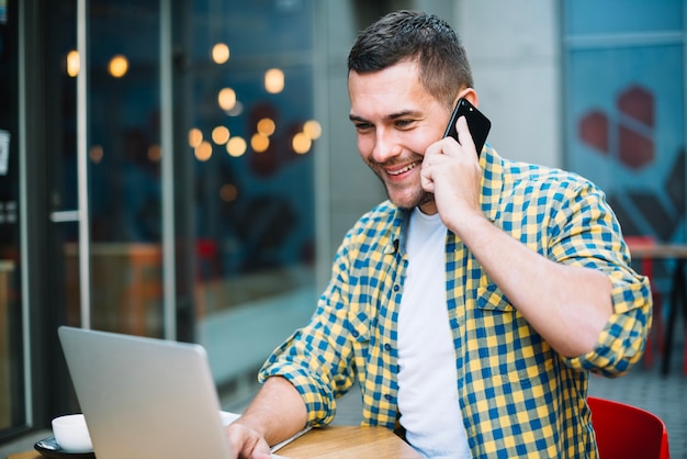 Smiling man on phone relaxing in cafeteria