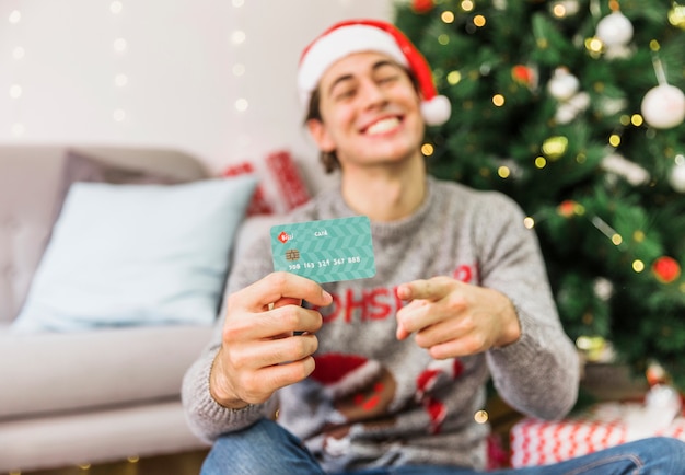 Free photo smiling man pointing at credit card