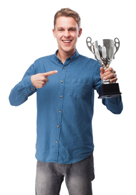 Smiling man pointing at a trophy