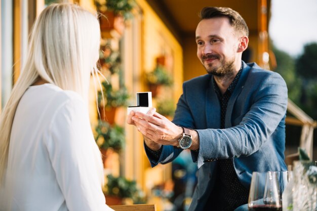 Smiling man proposing her girlfriend by giving engagement ring