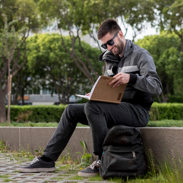 Smiling man reading book on street